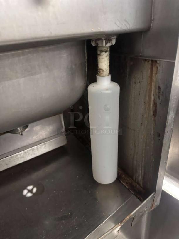 Commercial stainless steel hand wash sink with gooseneck faucet and built-in paper towel dispenser, fully operational.