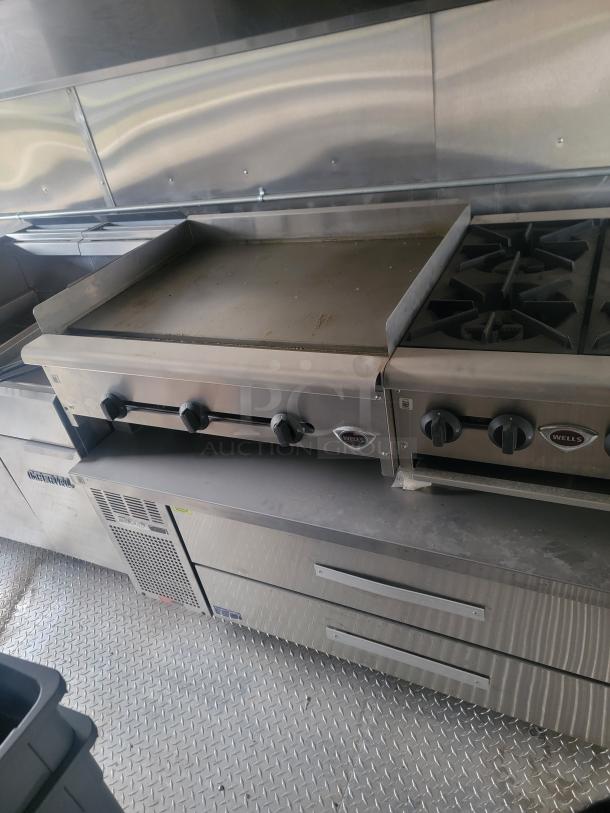 Rock Solid Cargo 24' mobile kitchen interior with Wells griddle, hot plate, Arctic Air refrigerator, CaptiveAire exhaust, needs cleaning.