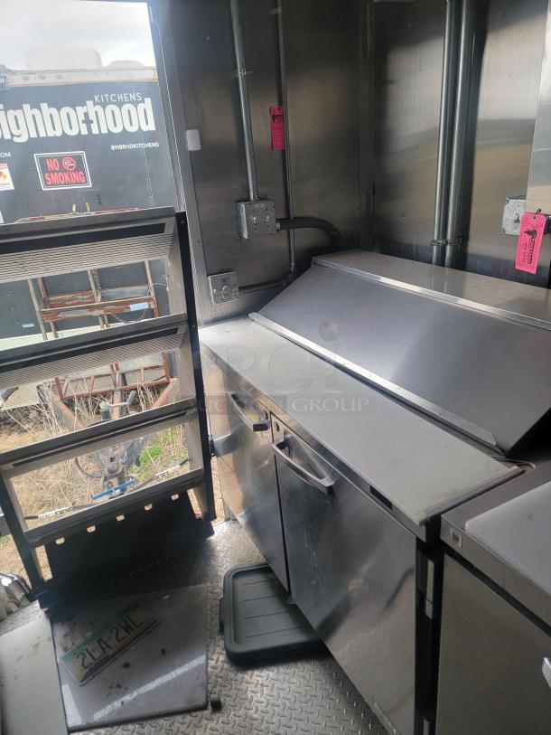 Professional 24' Rock Solid Cargo mobile kitchen trailer with griddle, reach-in fridge, and exhaust hood system. Needs cleaning.