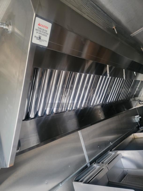 Interior of a 24' Rock Solid Cargo mobile kitchen trailer, featuring a CaptiveAire exhaust hood and stainless steel surfaces.