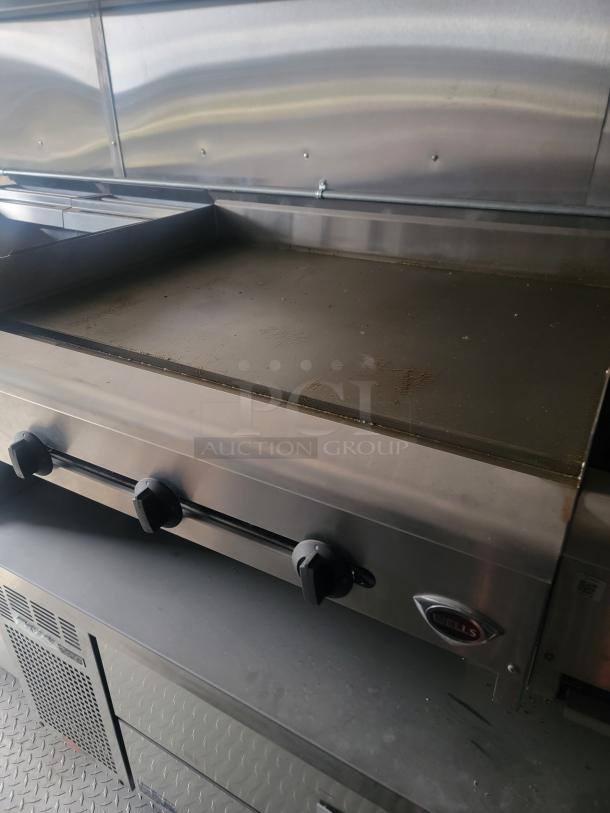 Wells countertop griddle inside a 24' Rock Solid Cargo mobile kitchen trailer, featuring stainless steel surface and control knobs.