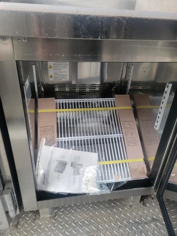 Rock Solid Cargo 24' Mobile Kitchen trailer interior, featuring a stainless steel storage compartment with manuals and equipment parts.