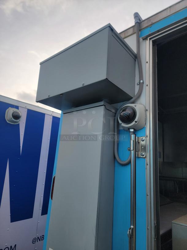 Exterior detail of a 2020 24' Diamond Cargo mobile kitchen, featuring a camera and electrical panel. Image shows some wear.
