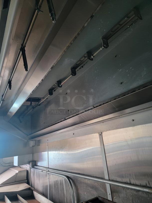 Interior view of a 2020 Diamond Cargo mobile kitchen with stainless steel surfaces and industrial piping. Needs cleaning.