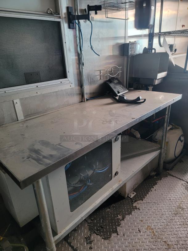 Diamond Cargo mobile kitchen interior, stainless steel prep station, storage cabinet, visible phone, needs cleaning.