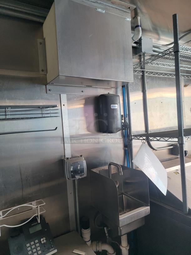 Professional-grade mobile kitchen interior of a 2020 24' Diamond Cargo. Features stainless steel surfaces, wash station, and equipment.