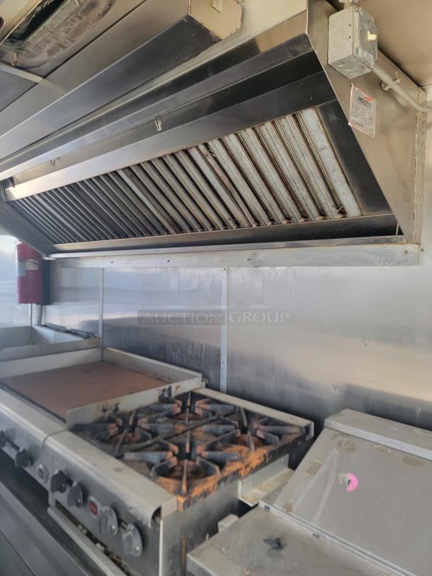 2019 Diamond Cargo 24' food trailer featuring stainless steel walls, ventilation hood, stove, and 3-compartment sink, needs cleaning.