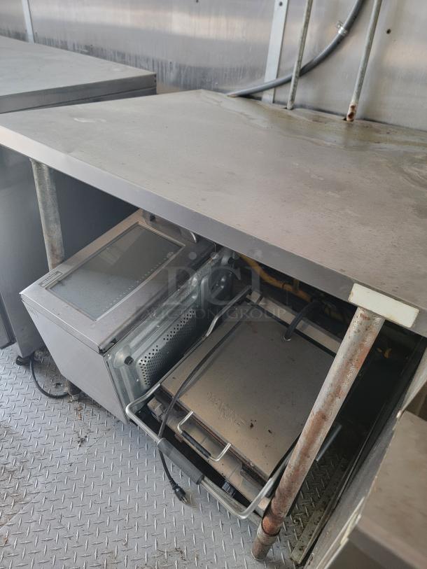 2019 Diamond Cargo 24' food trailer interior, featuring stainless steel surfaces, ventilation hood, and appliances; needs cleaning.