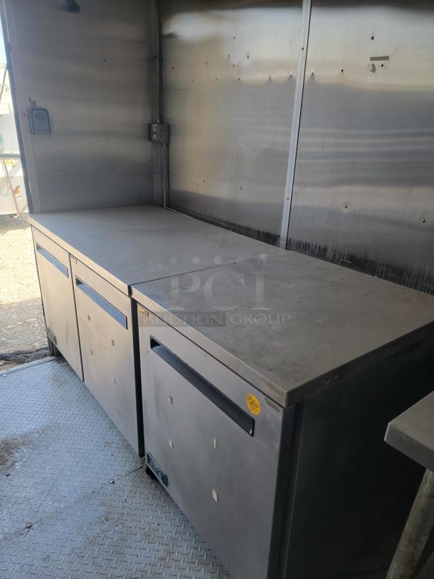 2019 24' Diamond Cargo food trailer interior, featuring stainless steel walls, counters, and Arctic Air units; needs cleaning.