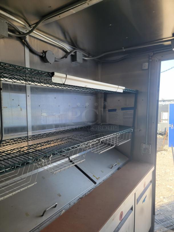 2019 Diamond Cargo 24' food trailer interior, featuring stainless steel walls, ventilation hood, and Arctic Air refrigeration. Needs cleaning.