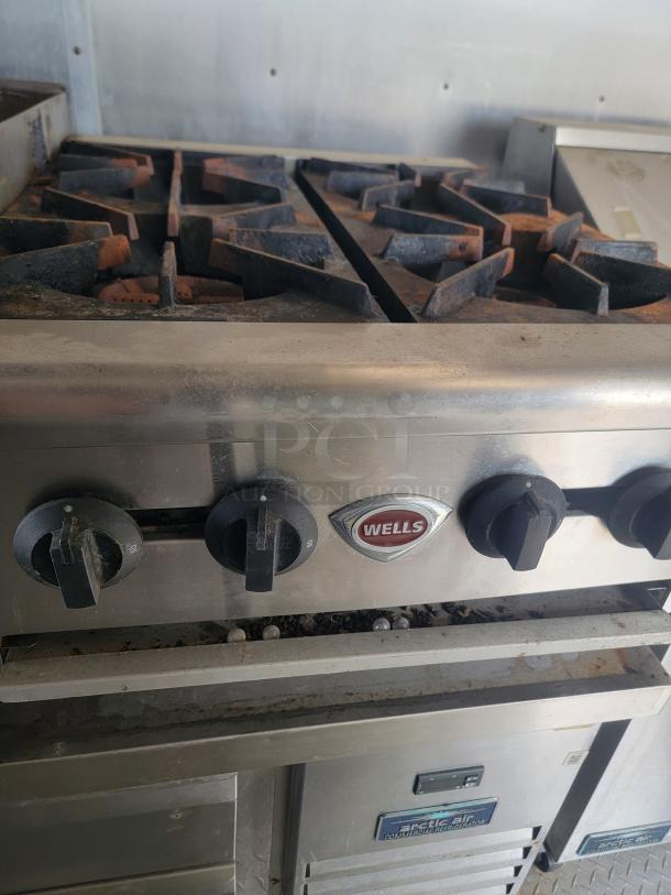 Wells commercial stove in a 2019 Diamond Cargo food trailer, featuring worn but functional knobs and visible Arctic Air refrigeration unit.