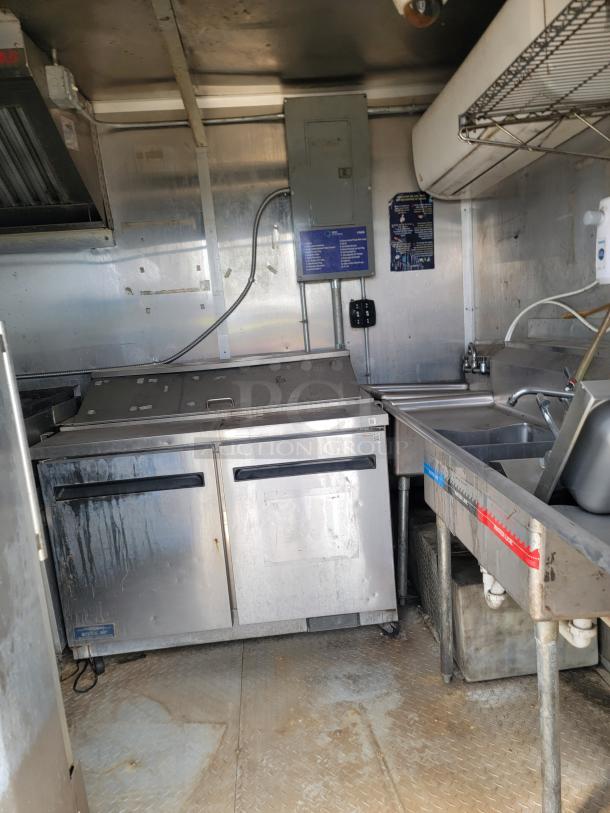 2019 Diamond Cargo 8.5x24 mobile kitchen interior with Arctic Air fridge, multi-compartment sink, and stainless exhaust hood. Needs cleaning.
