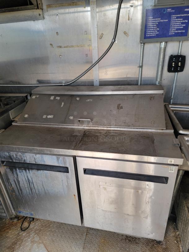 Diamond Cargo 8.5x24 mobile kitchen interior, showcasing a stainless steel Arctic Air commercial fridge with visible wear.