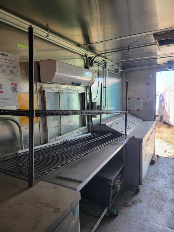 2019 Diamond Cargo 8.5x24 mobile kitchen interior with metal shelving, AC unit, and equipment. Needs cleaning.