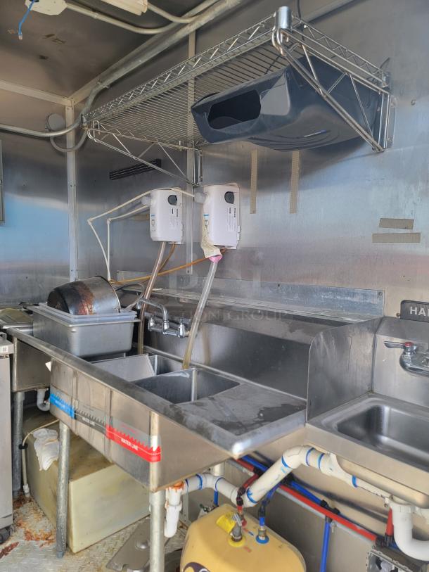 2019 Diamond Cargo mobile kitchen interior, featuring multi-compartment sink system, water heater, and stainless steel shelving.