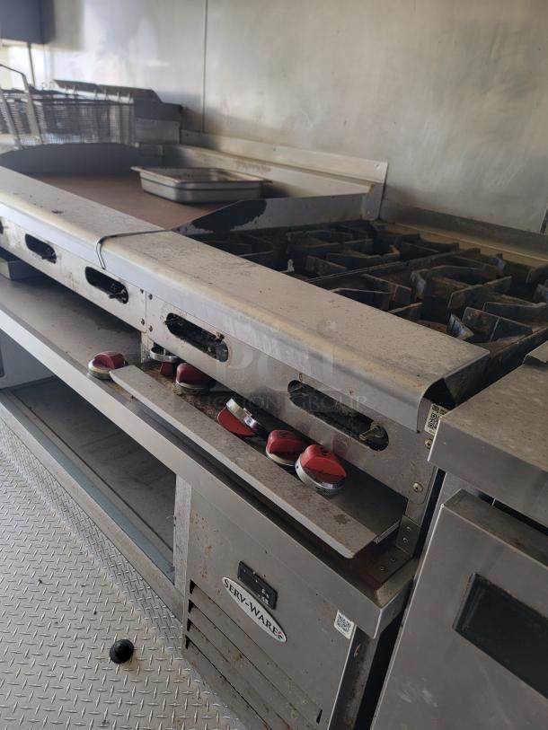 2019 Diamond Cargo 24' mobile kitchen interior with Serv-Ware equipment, showing professional stove and fryer in need of cleaning.