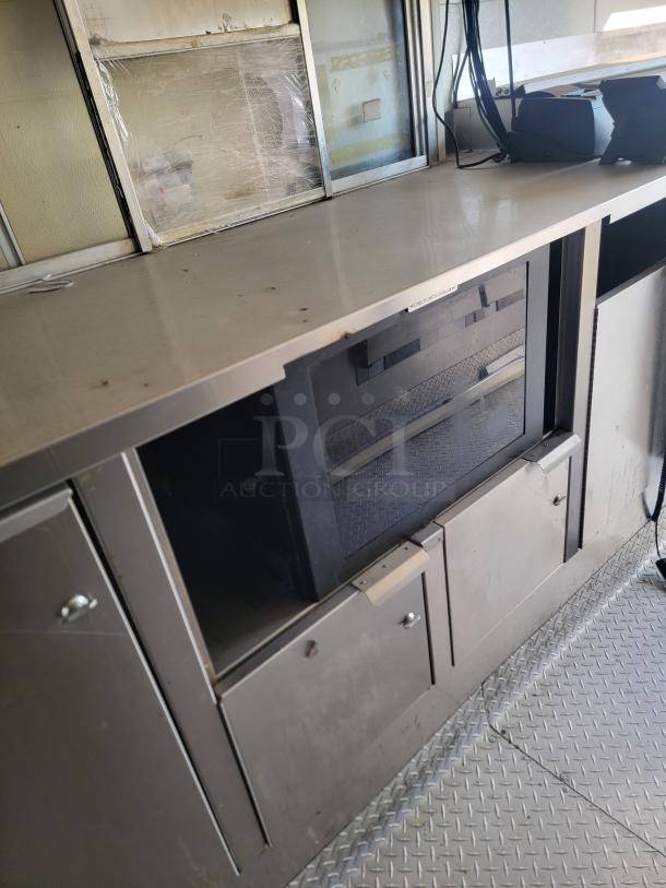 2019 Diamond Cargo 24' mobile kitchen interior. Features stainless steel counters, storage cabinets, and Serv-Ware equipment.