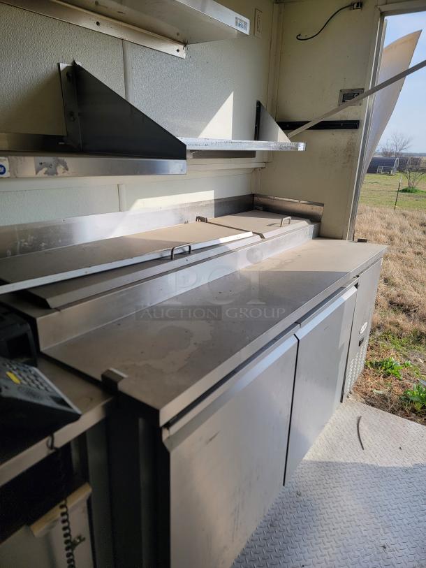 2019 Diamond Cargo 24' mobile kitchen interior with stainless steel Serv-Ware equipment, shelves, and refrigeration. Needs cleaning.