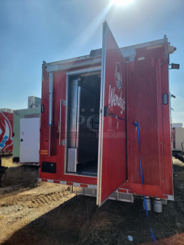 2022 Wendy’s 28' Rock Solid Cargo mobile kitchen trailer, triple-axle, 120/208V 3-phase, red exterior, open door.