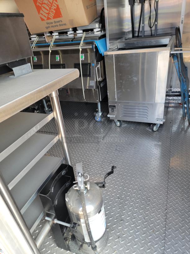 2022 Rock Solid Cargo 28' mobile kitchen interior, featuring stainless steel appliances, shelving, and electrical system.