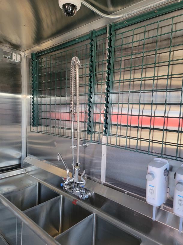 2022 Rock Solid Cargo mobile kitchen interior with stainless steel triple sink, industrial faucet, and soap dispensers.
