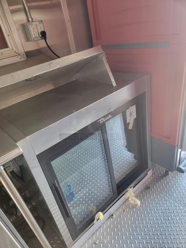 2022 Rock Solid Cargo 28' mobile kitchen interior, featuring a True commercial display refrigerator and durable diamond plate flooring.