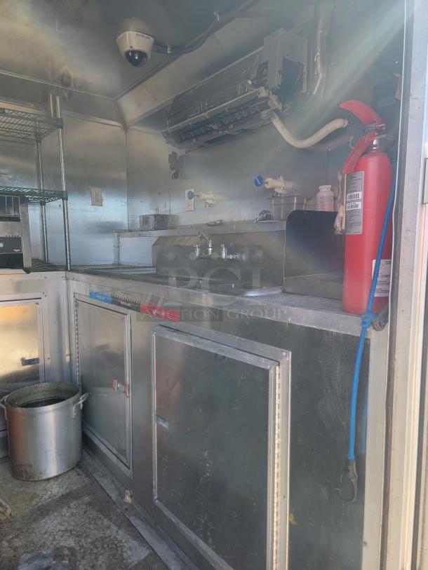 2019 Peach Cargo 24' mobile kitchen interior with stainless steel counters, sink, storage cabinets, and fire extinguisher.