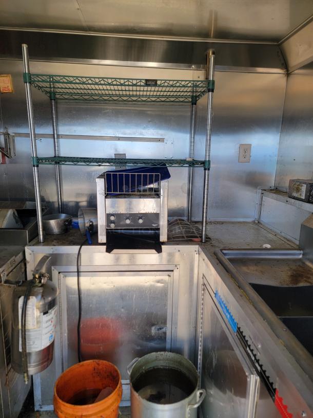 Interior of a 2019 Peach Cargo 24' mobile kitchen showing stainless steel counters, shelving, and a cooking unit.
