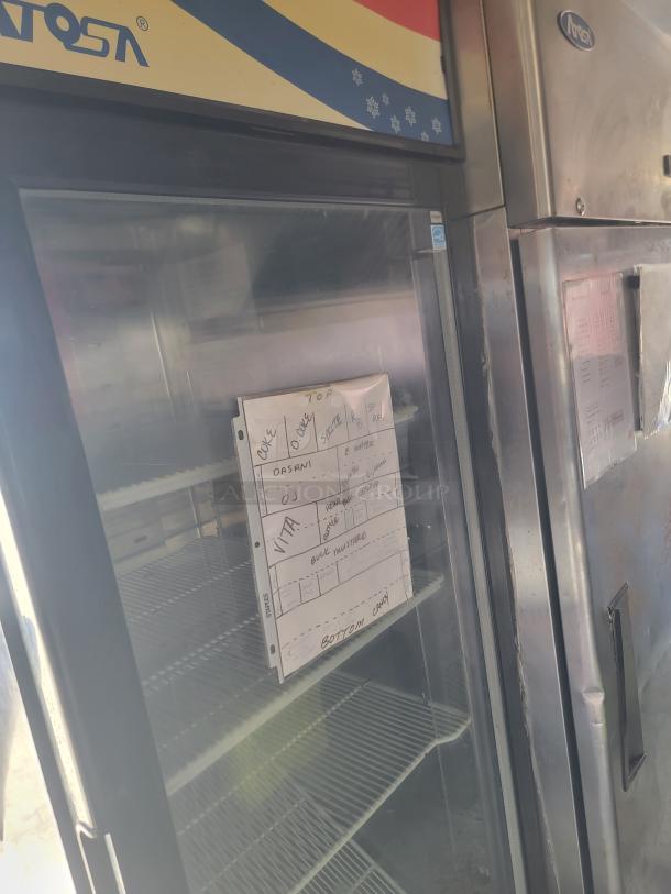 Peach Cargo 24' mobile kitchen interior, featuring Atosa fridge with shelving and labeled inventory sheet, indicating setup.