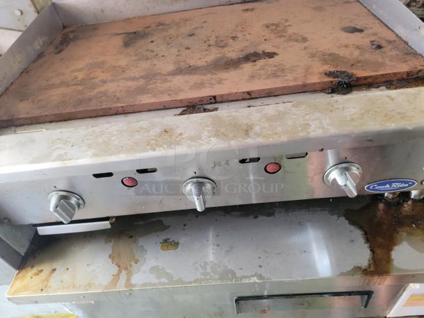 CookRite commercial grill in a Peach Cargo mobile kitchen, showing worn condition with grease marks and control knobs.