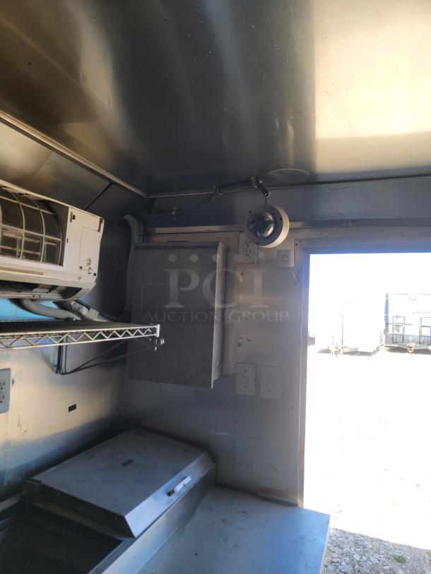 Interior view of 2019 Peach Cargo 24' mobile kitchen with stainless steel surfaces, shelving, and wiring, ready for customization.
