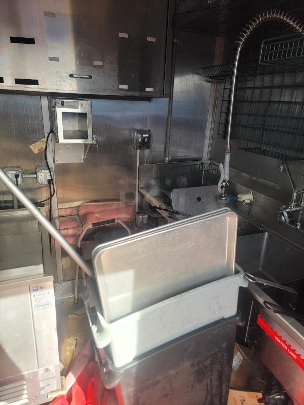 Interior of a 2021 Titanium Cargo 28’ Mobile Kitchen with commercial-grade equipment, including a 3-compartment sink and electrical panels.