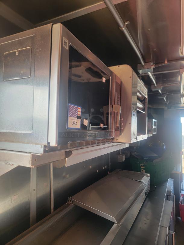 Inside view of a Titanium Cargo 28' mobile kitchen featuring a Menumaster oven with USA marking, stainless steel counters, and professional equipment.