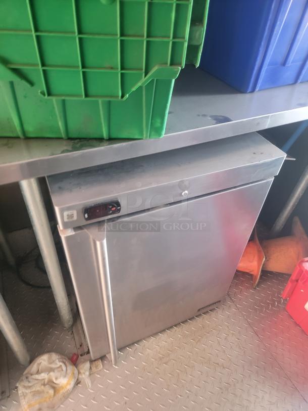 Stainless steel professional refrigerator inside a 2021 Titanium Cargo 28' Mobile Kitchen. Features sturdy shelving.