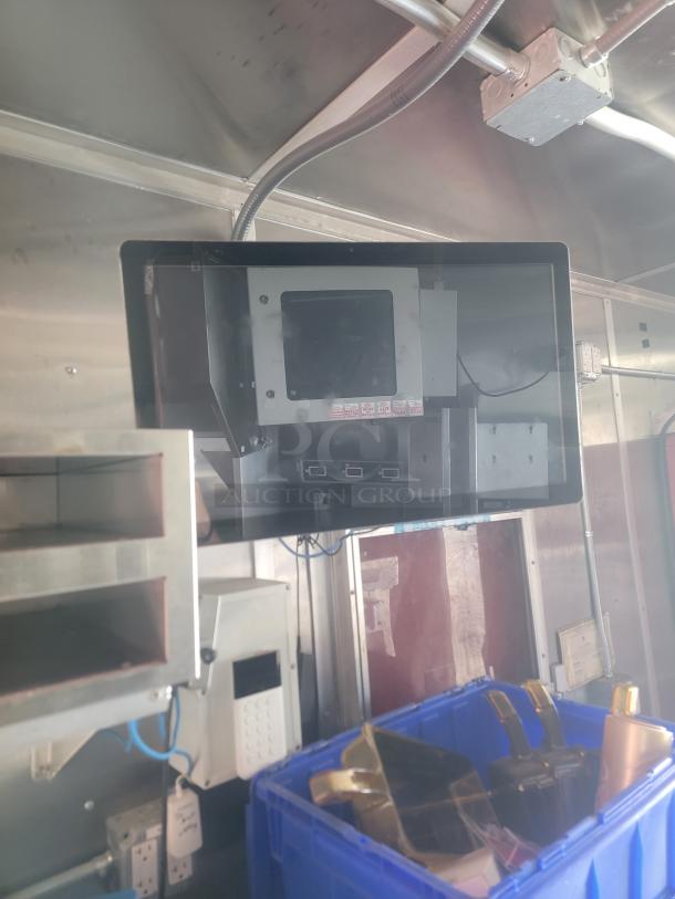 Interior view of 2021 Titanium Cargo 28' Mobile Kitchen, showing electronic equipment panel, outlets, and storage bins.