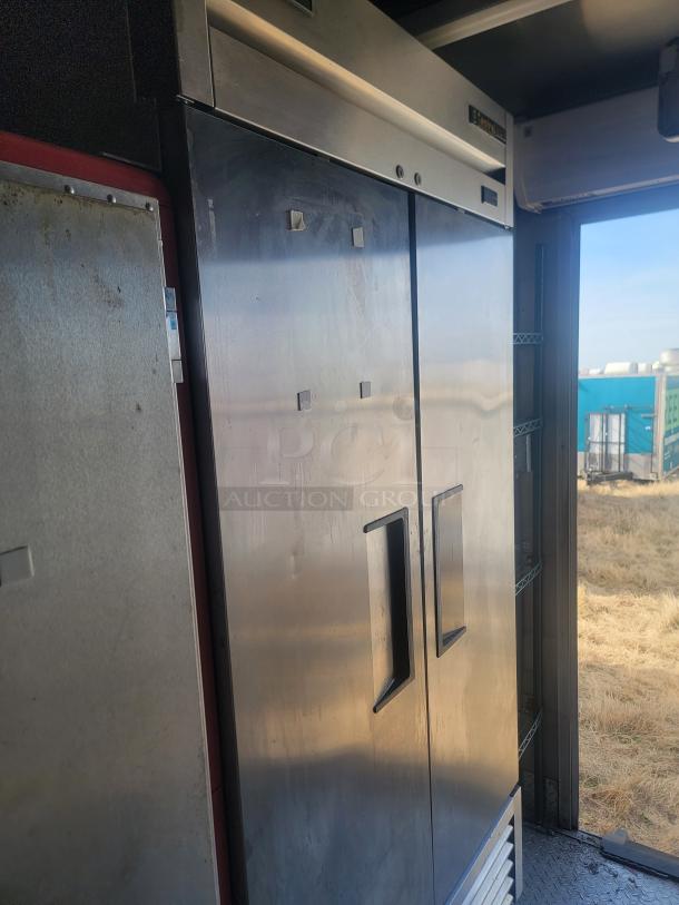 Interior view of a 2021 Titanium Cargo Mobile Kitchen featuring stainless steel commercial refrigeration.