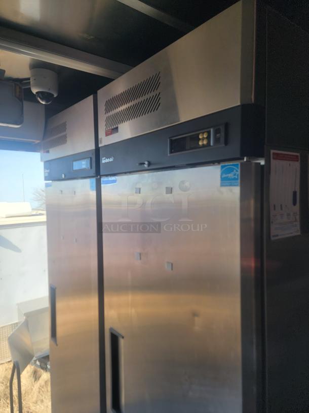 2021 Titanium Cargo 28' Mobile Kitchen interior with stainless steel commercial fridge, security camera, and control panels.