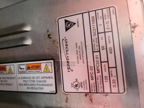 Label on Henny Penny fryer model MPC-22, serial GC211056. Displays specs: 400 watts, 120 volts, 60 Hz. Warning for hot surface.