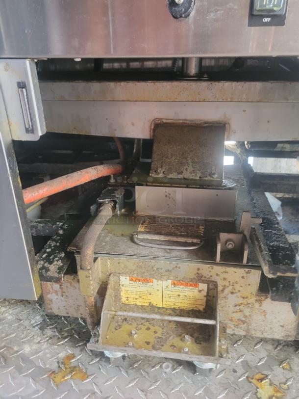 Close-up of interior grill section on a 2021 Titanium Cargo 28' Mobile Kitchen, showing clamshell grill with visible wear and warning labels.