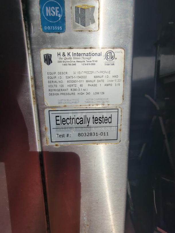 Metal tag on a 34" meat freezer with propane by H&K International. Includes serial number 8032831-011, electrically tested label.