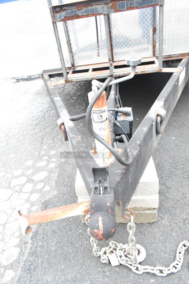 Trailer hitch of a 2021 Rock Solid Cargo 24' fast food trailer with Bulldog label. Rust visible on hitch and chain.