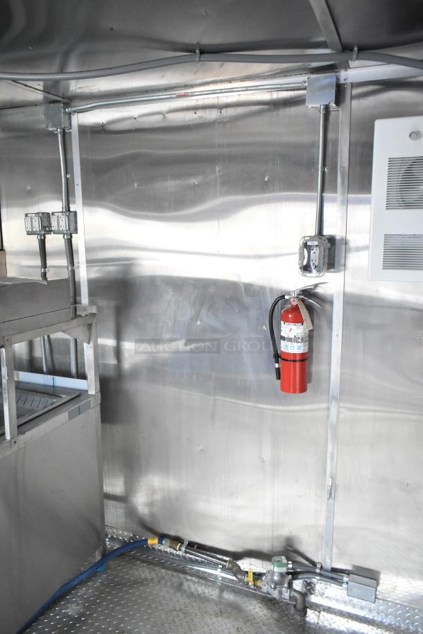 2021 Rock Solid Cargo 24' mobile kitchen trailer interior. Features stainless steel walls, electrical outlets, and a fire extinguisher. Brand new condition.