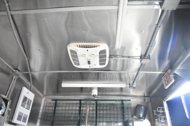 Interior view of a 2021 Rock Solid Cargo 24' mobile kitchen, featuring a CaptiveAire grease hood, stainless steel walls, and utility fixtures.