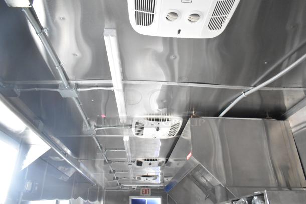 Interior of a brand new 2021 Rock Solid Cargo 24' fast food trailer. Features stainless steel walls, ceiling vents, and a CaptiveAire grease hood.