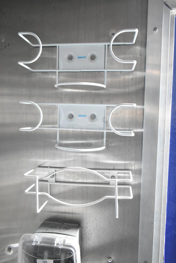 Interior view of a Rock Solid Cargo fast food trailer showcasing mounted wire racks and Ecolab branding on a stainless steel surface.