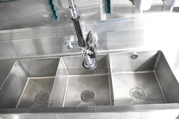 Stainless steel triple sink with commercial faucet in a new Rock Solid Cargo mobile kitchen trailer.