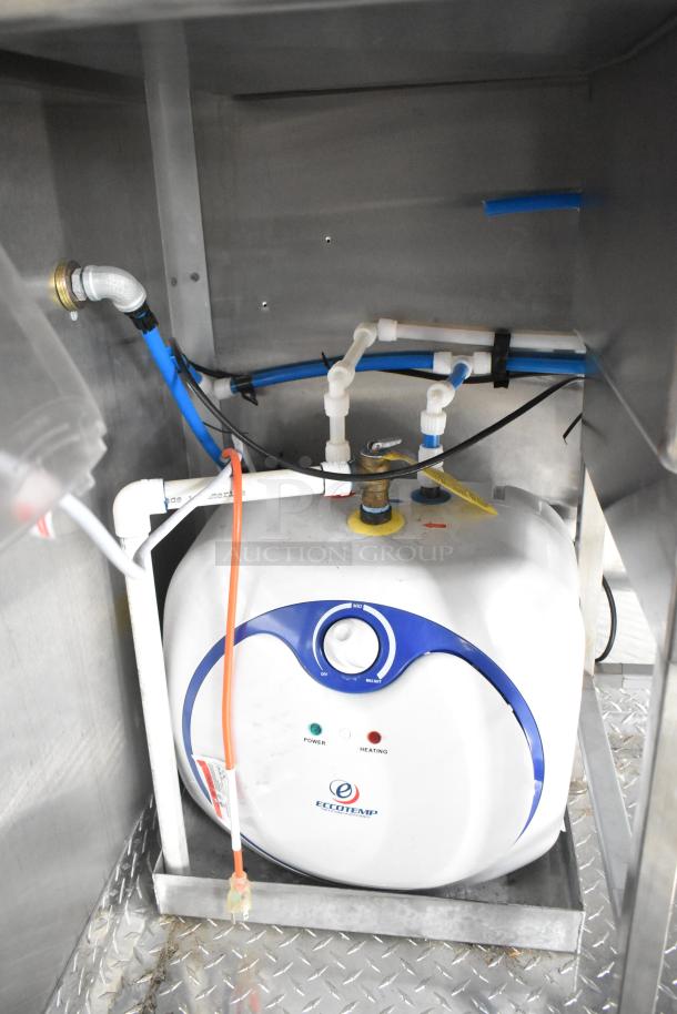 Interior of Rock Solid Cargo trailer with an Eccotemp water heater, featuring power and heating indicators, set on diamond plate flooring.