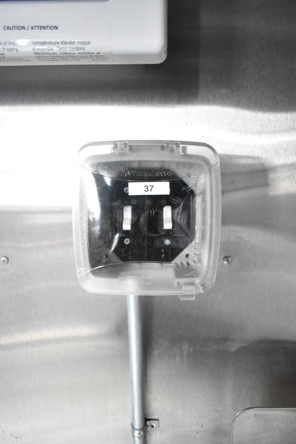 Electrical switches labeled "Intermatic" with protective cover and number "37," in a mobile kitchen trailer.