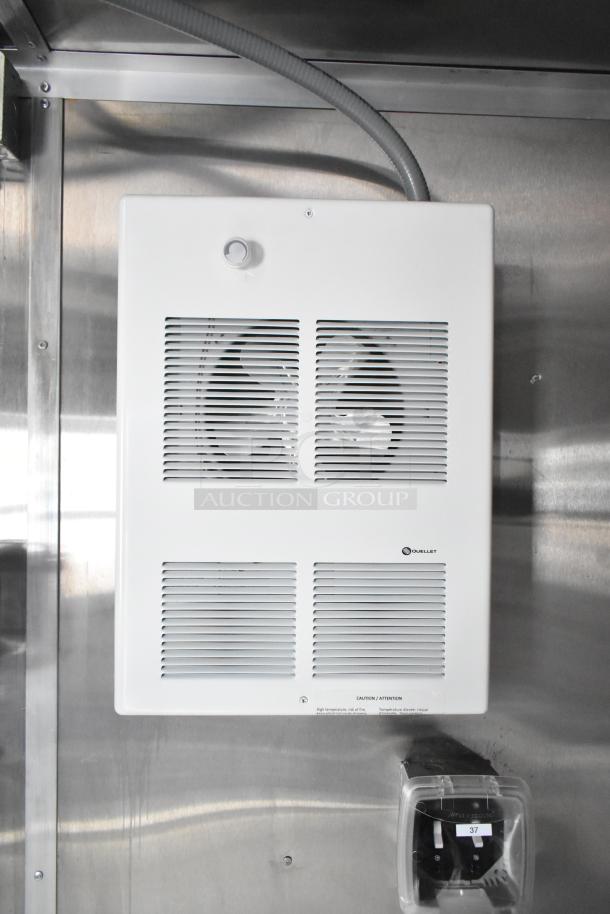 Inside view of Rock Solid Cargo 24' mobile kitchen trailer, featuring a wall-mounted Ouellet heater and electrical components.