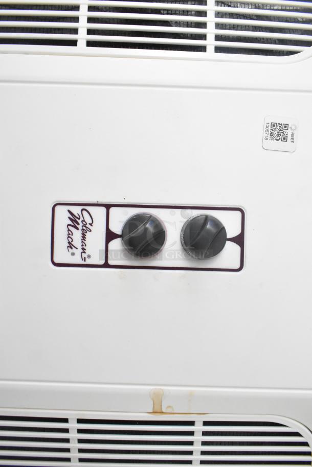 White Coleman-Mach control panel with dual dials on a fast food trailer. Features QR code label.